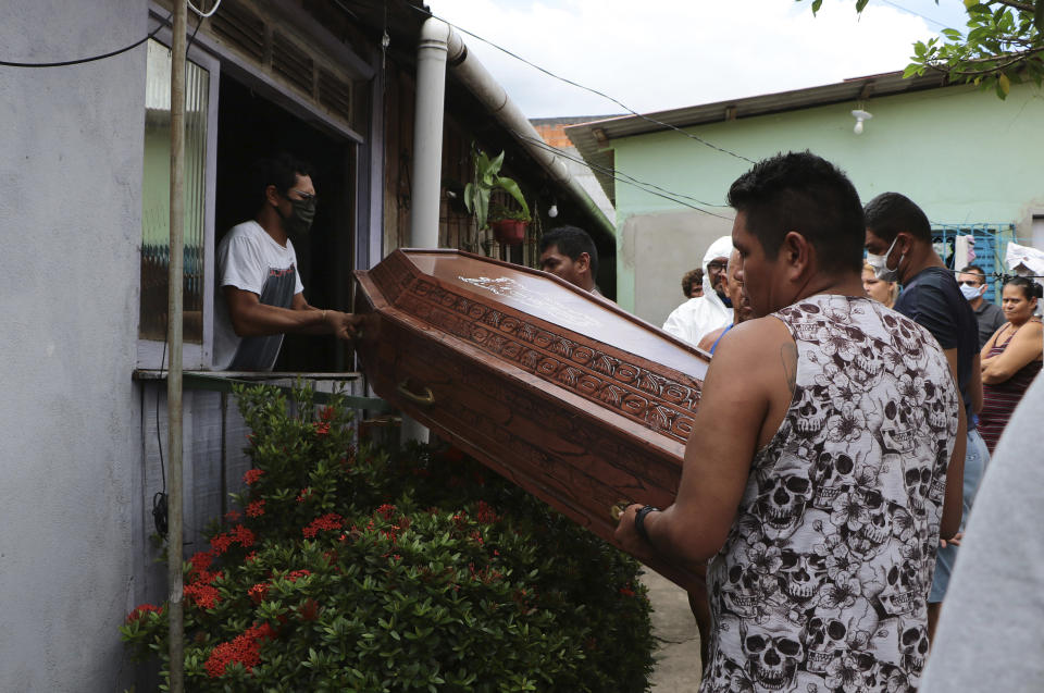 Relatives and funeral workers in protection gear move the coffin containing the remains of Raimundo Costa do Nascimento, 86, through a window of his to a hearse in Sao Jorge, Manaus, Brazil, Thursday, April 30, 2020. Costa do Nascimento died of pneumonia in his Manaus home. Family members had to wait 10 hours for funerary services to come pick up his body. (AP Photo/Edmar Barros)
