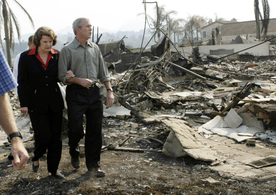 FILE - President George W. Bush, right, escorts U.S. Sen. Dianne Feinstein, D-Calif., as they walk through the remains of a home that was damaged by the California wildfires, Thursday, Oct. 25, 2007, in San Diego. (AP Photo/Pablo Martinez Monsivais, File)