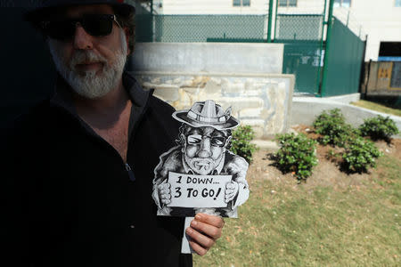 Thom Karamus, a New Orleans artist, stands with a sign he made in front of the foundation where the Battle of Liberty Place monument, built in 1891 to commemorate a battle between the Crescent City White League and New Orleans biracial police force, was removed early Monday morning in New Orleans Louisiana, U.S., April 24, 2017. REUTERS/Ben Depp