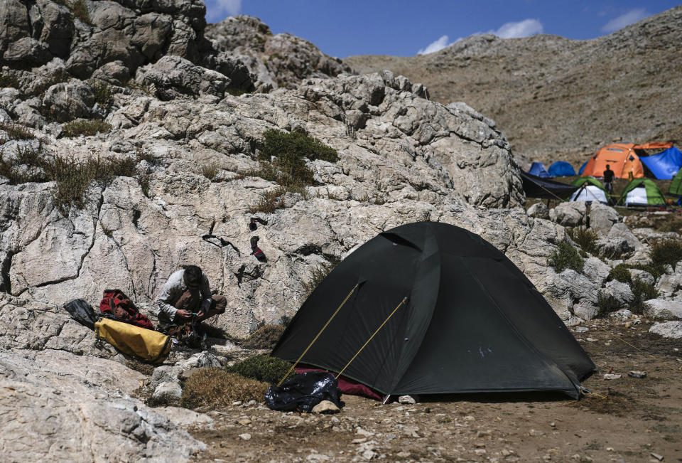 A rescuer works on her hiking gear in the European Cave Rescue Association (ECRA) members, camp next to the Morca cave during a rescue operation near Anamur, south Turkey, Saturday, Sept. 9, 2023. American researcher Mark Dickey, 40, who fell ill almost 1,000 meters (more than 3,000 feet) below the entrance of a cave in Turkey, has recovered sufficiently enough to be extracted in an operation that could last three or four days, a Turkish official was quoted as saying on Friday. (AP Photo/Khalil Hamra)
