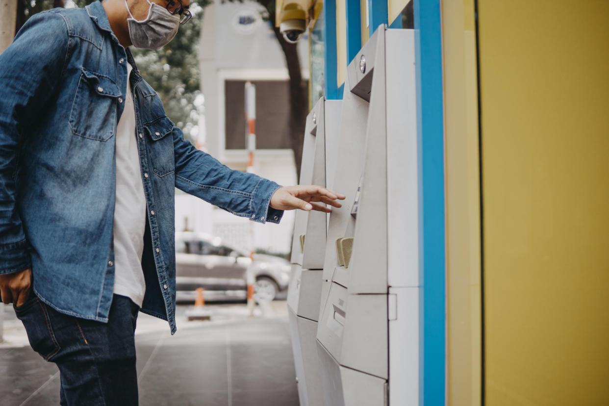 Young asian man wearing medical mask withdraw money from bank cash machine with debit card - Senior male doing payment with credit card in ATM - Concept of business, banking account and lifestyle people