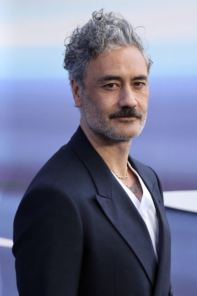 Taika Waititi poses in a formal suit with a white shirt at an event