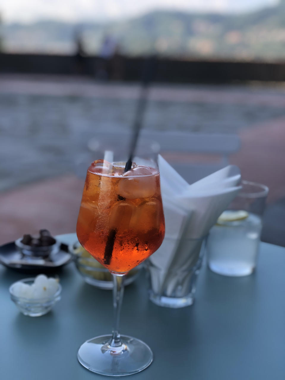 A glass of iced drink on a table with napkins and small dishes in the background