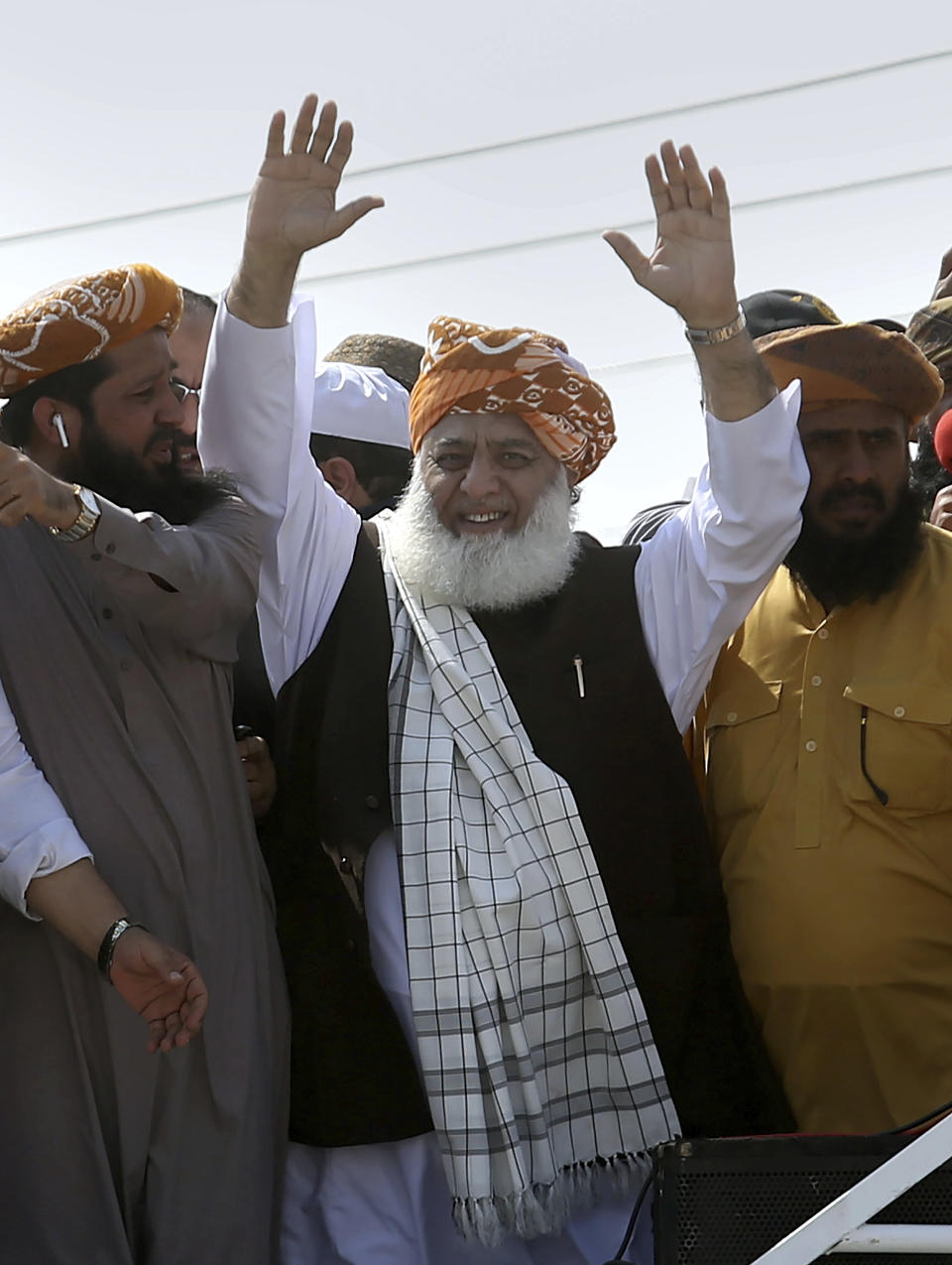 Maulana Fazlur Rehman, center, head of the Jamiat Ulema-e-Islam party, waves to supporters on his arrival to lead an anti-government march, in Karachi, Pakistan, Sunday, Oct. 27, 2019. Thousands of supporters of the ultra-religious party are gathering in Karachi to start a large anti-government march on Pakistan's capital farther north. (AP Photo/Fareed Khan)