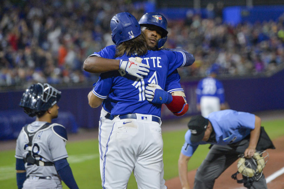 Toronto Blue Jays' Vladimir Guerrero Jr., center right, hugs Bo Bichette after hitting a two-run home run against the Tampa Bay Rays during the seventh inning of a baseball game in Buffalo, N.Y., Friday, July 2, 2021. (AP Photo/Adrian Kraus)