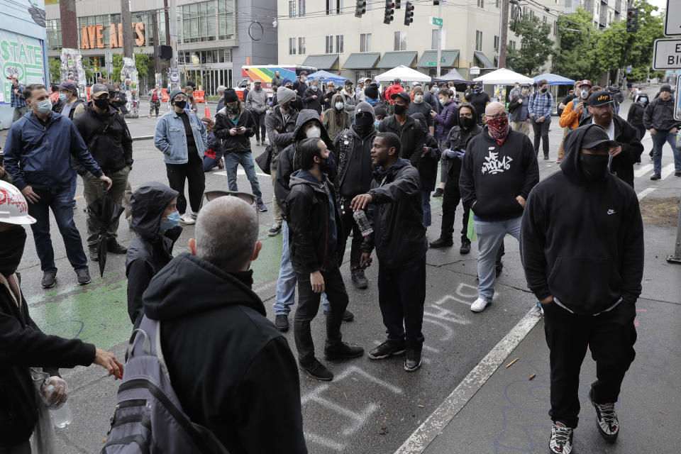 People gather and have discussions outside the Seattle Police Dept. East Precinct building, which has been boarded up and abandoned except for a few officers inside, Thursday, June 11, 2020, inside what is being called the "Capitol Hill Autonomous Zone" in Seattle. Following days of violent confrontations with protesters, police in Seattle have largely withdrawn from the neighborhood, and protesters have created a festival-like scene that has President Donald Trump fuming. (AP Photo/Ted S. Warren)