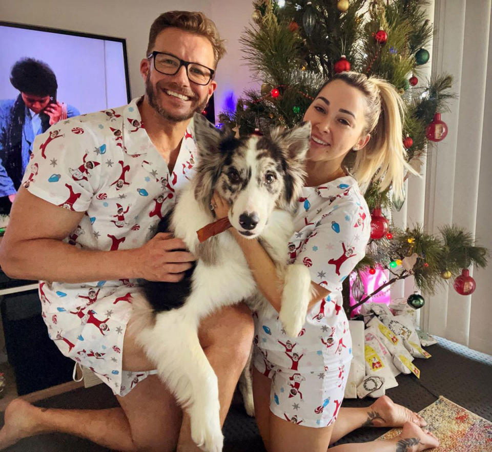 Luke Jacobz and Raychel Stuart holding their dog at Christmas