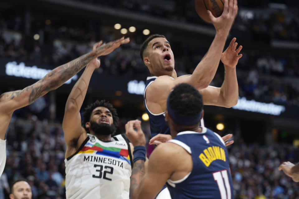 Denver Nuggets forward Michael Porter Jr. shoots between forward Bruce Brown, front, and Minnesota Timberwolves center Karl-Anthony Towns during the second half of Game 2 of an NBA basketball first-round playoff series Wednesday, April 19, 2023, in Denver. (AP Photo/David Zalubowski)