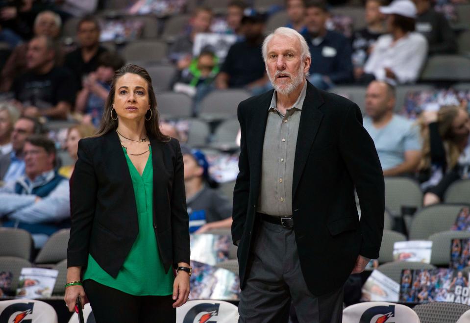 San Antonio Spurs assistant coach Becky Hammon and Spurs head coach Gregg Popovich watch their team warm up before a game against the Dallas Mavericks at the American Airlines Center.