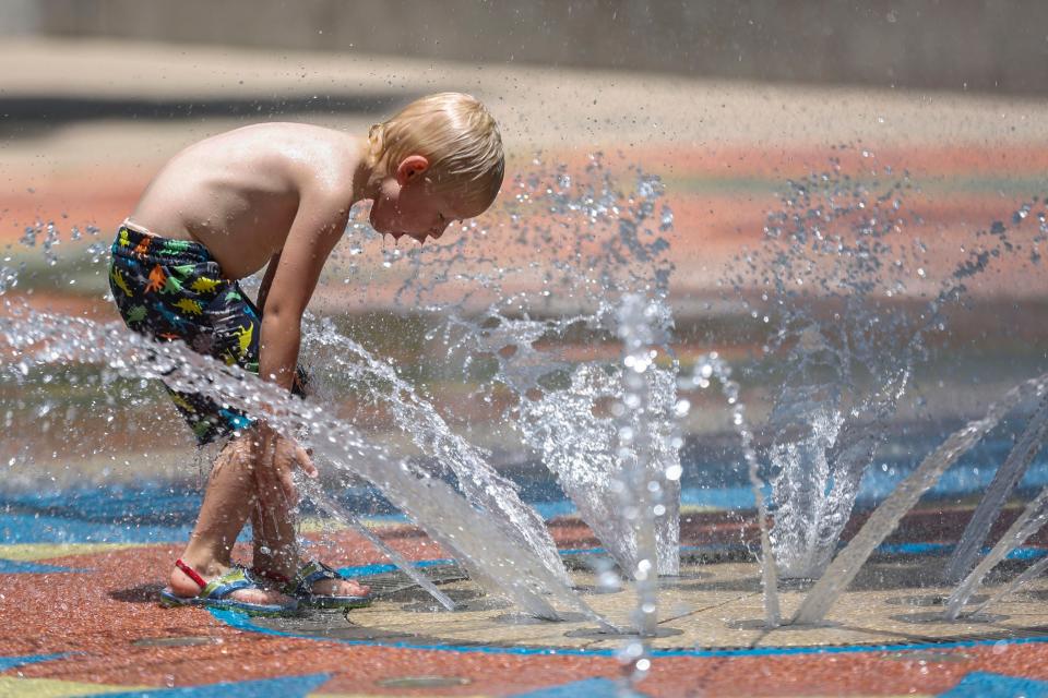 Granger Claassen plays in the water at the Myriad Botanical Gardens fountains. Temperatures Friday hovered near 100 degrees.