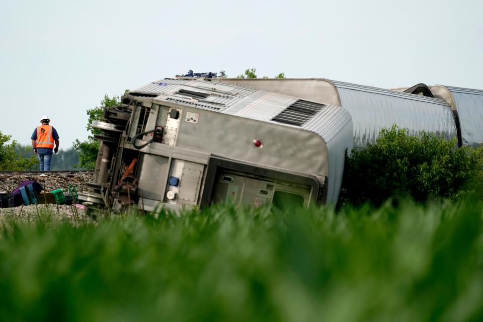 A worker inspects the scene of an Amtrak train which derailed after striking a dump truck, Monday, June 27, 2022, near Mendon, Mo. 