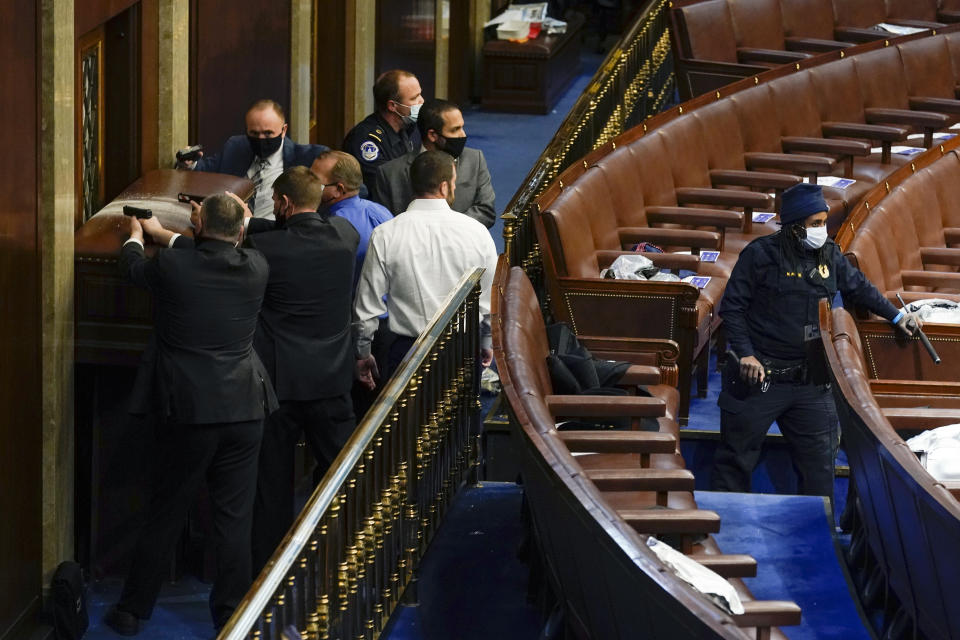 U.S. Capitol Police with guns drawn stand near a barricaded door as rioters try to break into the House Chamber at the U.S. Capitol on Wednesday, Jan. 6, 2021, in Washington. (AP Photo/Andrew Harnik)
