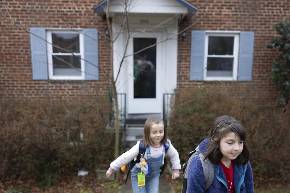 Natalia Bednar, left, exits her home beside her sister Valencia before riding a bus to school, Friday, Feb. 2, 2024, in Chevy Chase, Md. (AP Photo/Tom Brenner)