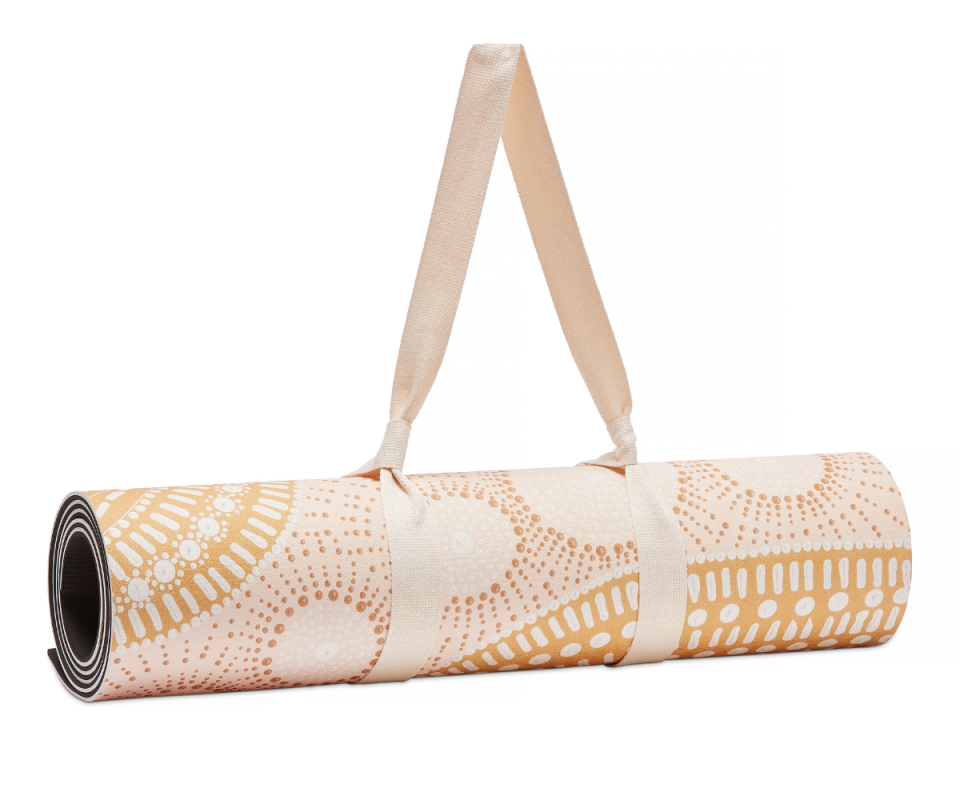 A rolled yoga mat in a pale pink and orange pastel indigenous pattern.