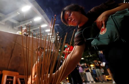 A woman burns incense as people gather to form a human chain during the Mid-Autumn Festival at Lennon Wall at Admiralty district in Hong Kong