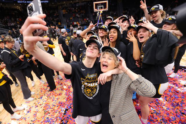 <p>Tyler Schank/NCAA Photos via Getty Images</p> Caitlin Clark takes selfie with coach Lisa Bluder after victorious game against the Louisville Cardinals in March 2023.