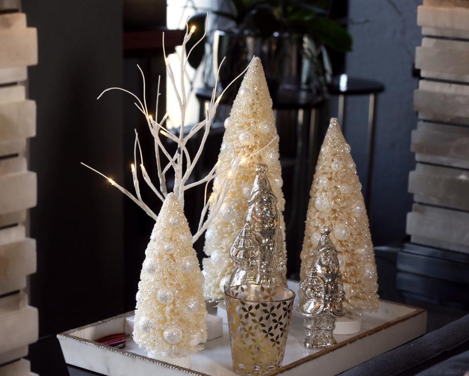 Miniature Christmas trees and birch twinkle trees are set on a table in the living room at Mitchell Conklin's apartment.