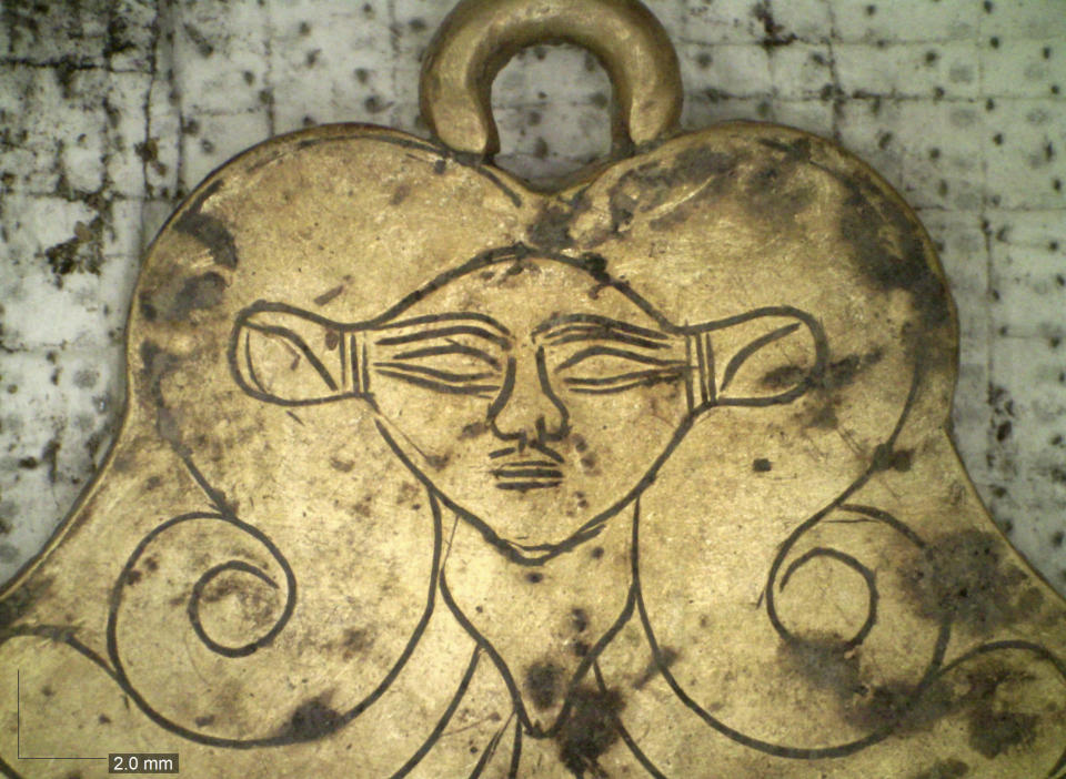 In this undated photo provided by the Greek Culture Ministry on Tuesday, Dec. 17, 2019, a golden pendant of the Egyptian goddess Hathor is seen that was found in a 3,500-year-old tomb discovered near the southwestern Greek town of Pylos. The ministry said American archaeologists have discovered two monumental royal tombs dating 3,500 years back, near a large Bronze Age palace that featured in Homer's Odyssey. Recovered grave goods included a golden seal ring and a golden Egyptian amulet. (Greek Culture Ministry via AP)