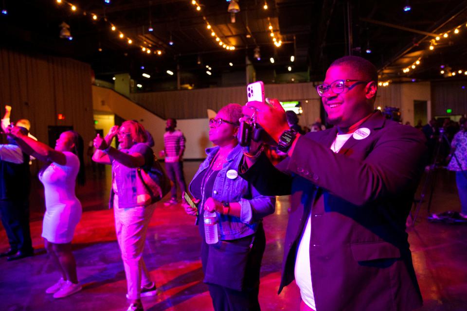 Dorcas Young Griffin, Paul Young’s sister, watches after early voting results for mayor are projected onto a screen showing Young in the lead as Keenan Lowery, a Paul Young supporter, takes a photo of the screen at an election watch party for Young at Minglewood Hall in Memphis, Tenn., on Thursday, October 5, 2023.