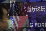 A man wearing a face mask to help curb the spread of the coronavirus sits near a screen showing delegates attend for the Lanting Forum on bringing China-U.S. relations back to the right track which chaired by Chinese Foreign Minister Wang Yi at the Ministry of Foreign Affairs office in Beijing on Monday, Feb. 22, 2021. Wang called on the U.S. Monday to lift restrictions on trade and people-to-people contacts while ceasing what Beijing considers unwarranted interference in the areas of Taiwan, Hong Kong, Xinjiang and Tibet. (AP Photo/Andy Wong)