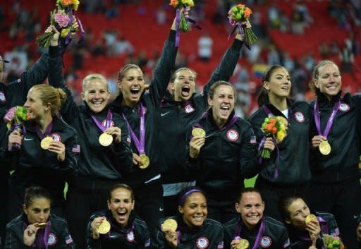 El plantel de fútbol femenino de Estados Unidos celebra exhibiendo a los fotógrafos la medalla de oro ganada tras vencer a Japón en la final de los Juegos de Londres 2012, el 9 de agosto de 2012 en el estadio Wembley de Londres. EEUU ganó su cuarto oro olímpico. (AFP | khaled desouki)