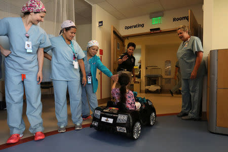 Andrea Destraio, 5, slaps hands with medical staff and invited police officers whose charity donated to Rady Children's Hospital to start a program that uses remote control cars to take young patients to the operating room, in San Diego, California, U.S. September 19, 2017. REUTERS/Mike Blake