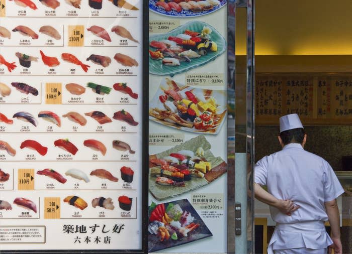 A chef next to a sushi restaurant in Japan.