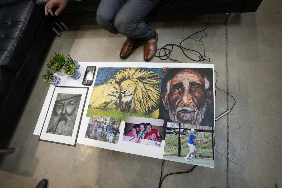 A display of artwork and family photographs sits on a table after Simon Glass and his wife, Sally, talked about the $19-million settlement from state and local law enforcement agencies for the killing of the couple's 22-year-old son, Christian, in June 2022, while he suffered a mental health crisis on Tuesday, May 23, 2023, during a news interview in the offices of the couple's lawyers in Denver. As part of the settlement, training for law officers will change as well. (AP Photo/David Zalubowski)