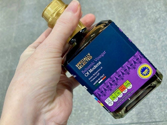bottle of modena specially selected balsamic vinegar with purple label in hand