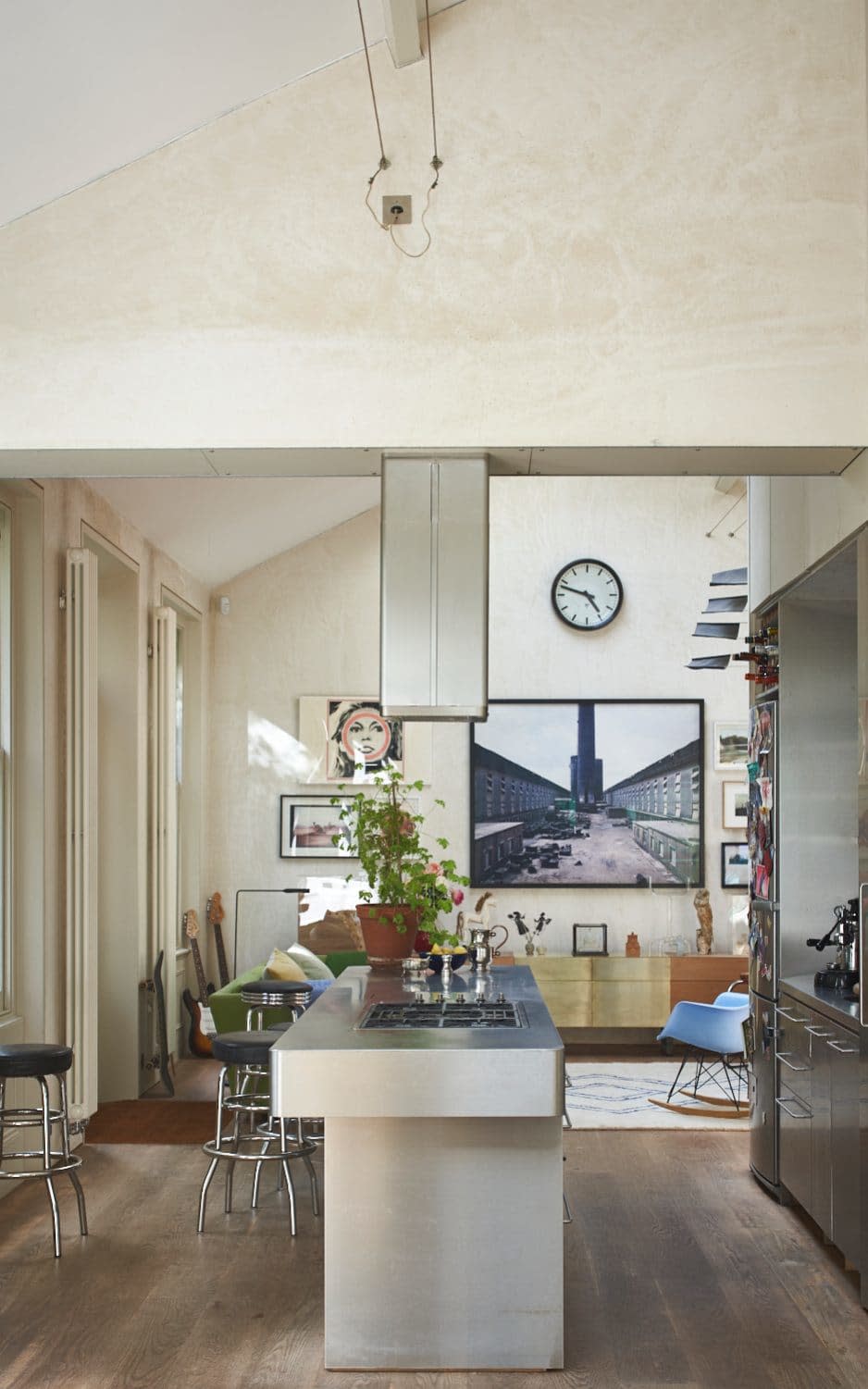 The stainless-steel cooking island is the centre of family life and doubles a s a cocktail bar when friends are over; the main photograph, by Edward Burtynsky, is of a Chinese aluminium factory; the Brigitte Bardot artwork is by Gerald Laing - james merrell