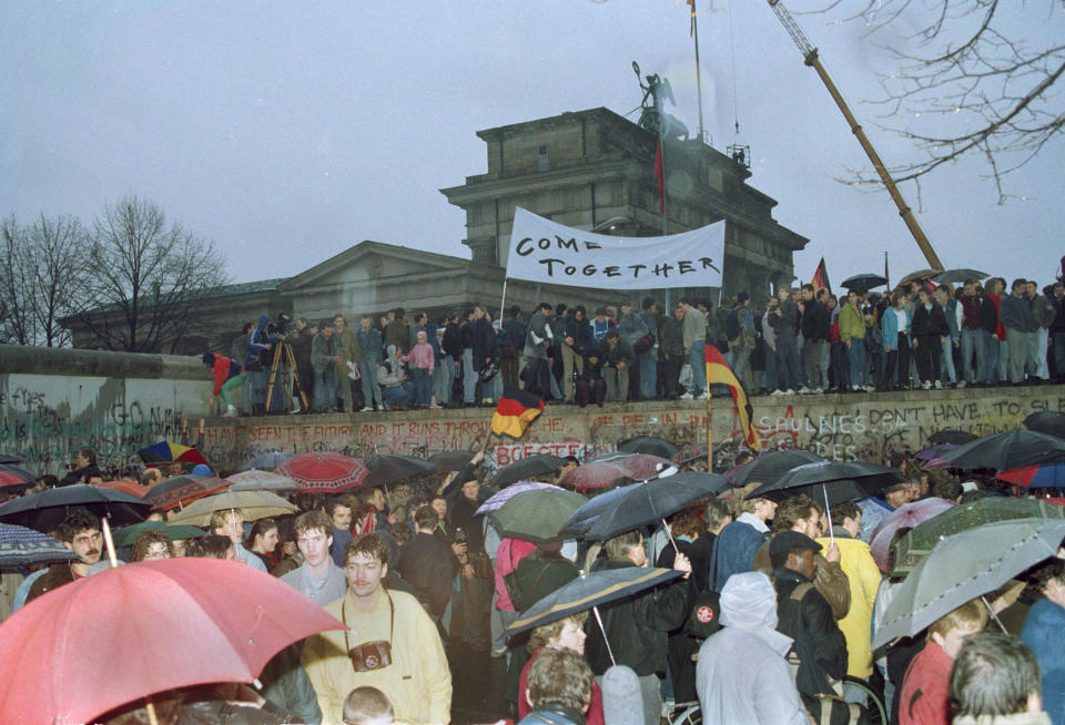 FILE - This Dec. 22, 1989 file photo shows thousands of Berliners crowding at the Brandenburg Gate and stand on top of the Berlin Wall after two new crossings were made, reuniting the divided city after 28 years. In 2014, Berlin will mark 25 years since the wall was breached. Events and exhibits commemorating the anniversary will include an installation of illuminated balloons on a 7.5-mile path where Berlin was once divided by the wall into East and West. (AP Photo/Michel Lipchitz, File)
