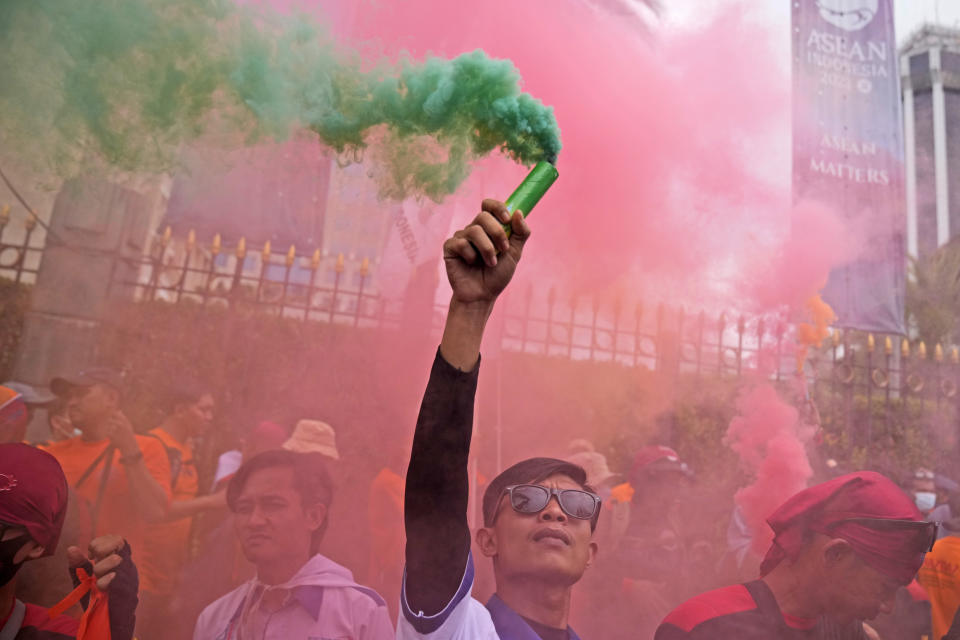 A worker holds up a smoke stick during a May Day rally in Jakarta, Indonesia, Monday, May 1, 2023. Workers and activists across Asia are marking May Day with protests calling for higher salaries and better working conditions, among other demands. (AP Photo/Dita Alangkara)