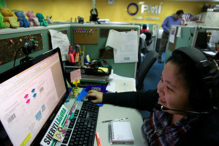 FILE PHOTO: A call center agent talks to a client in the U.S. as she works the overnight shift in Manila's Makati financial district February 6, 2012. REUTERS/Erik De Castro/File Photo