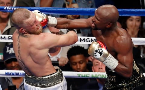 Floyd Mayweather Jr. hits Conor McGregor in a super welterweight boxing match in Las Vegas - Credit: AP Photo/Eric Jamison