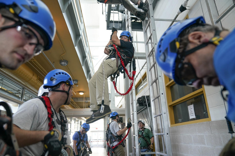 FILE - Lucas Drake, center, and other classmates practice techniques for working at heights during a Global Wind Organisation certification class at the Massachusetts Maritime Academy in Bourne, Mass., Aug. 2, 2022. A new report has found that clean energy now provides more employment than the fossil fuel industry, reflecting the shift that efforts to tackle climate change are having on the global jobs market. (AP Photo/Seth Wenig, File)