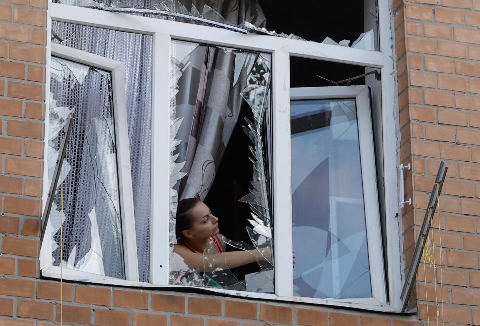 A woman stands by a damaged window of her flat in Kyiv (EPA)