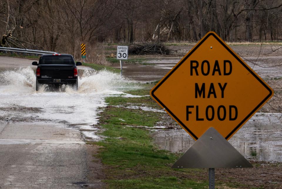 A motorist drives through a flooded road Saturday, March 25, 2023, after heavy rain in Yorktown, Ind. A partnership at Indiana University hopes to provide assistance to rural communities across the state that are dealing with the effects of climate change, such as flooding and extreme heat.