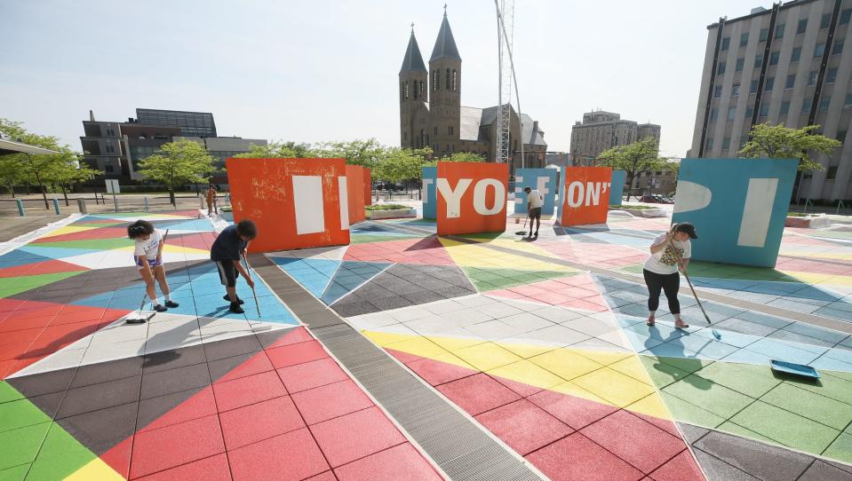 Members of the Boa Mistura team and community members work Monday on refreshing the paint at the STEM Plaza in Akron.