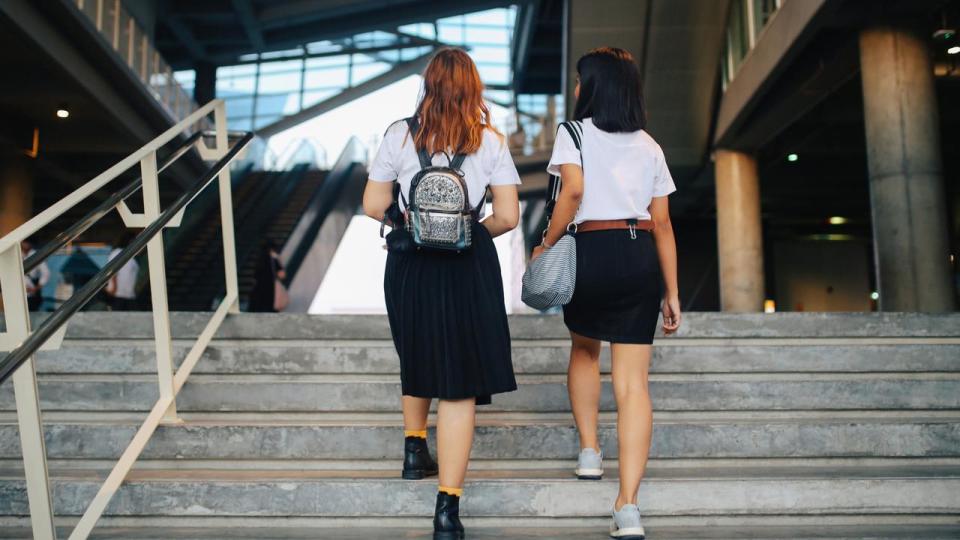 Two young Asian students in uniforms arriving at school or university