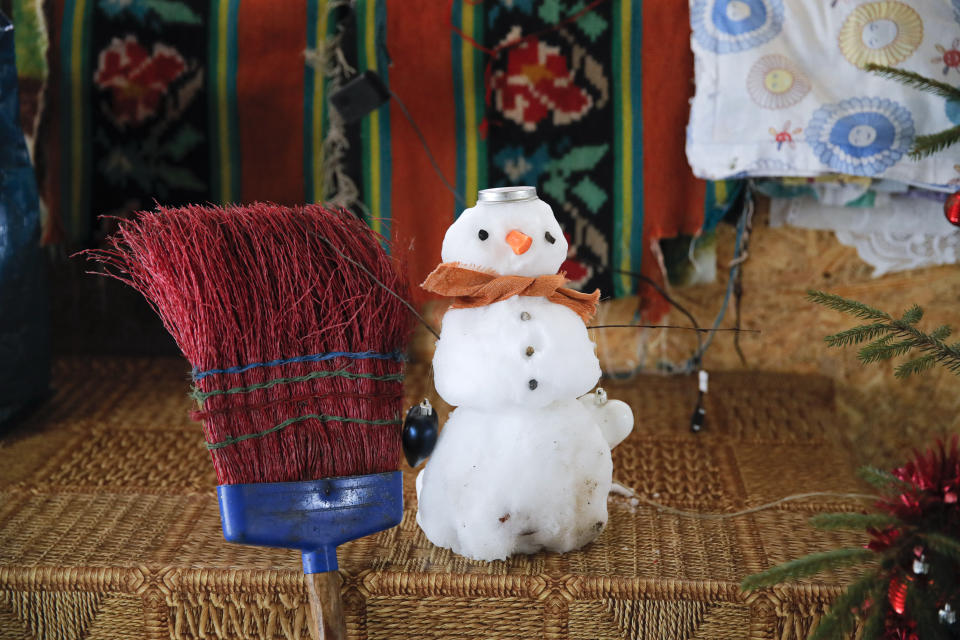 A small snowman made by children sits on a table if a house, in Nucsoara, Romania, Saturday, Jan. 9, 2021. Valeriu Nicolae and his team visited villages at the foot of the Carpathian mountains, northwest of Bucharest, to deliver aid. The rights activist has earned praise for his tireless campaign to change for the better the lives of the Balkan country’s poorest and underprivileged residents, particularly the children. (AP Photo/Vadim Ghirda)