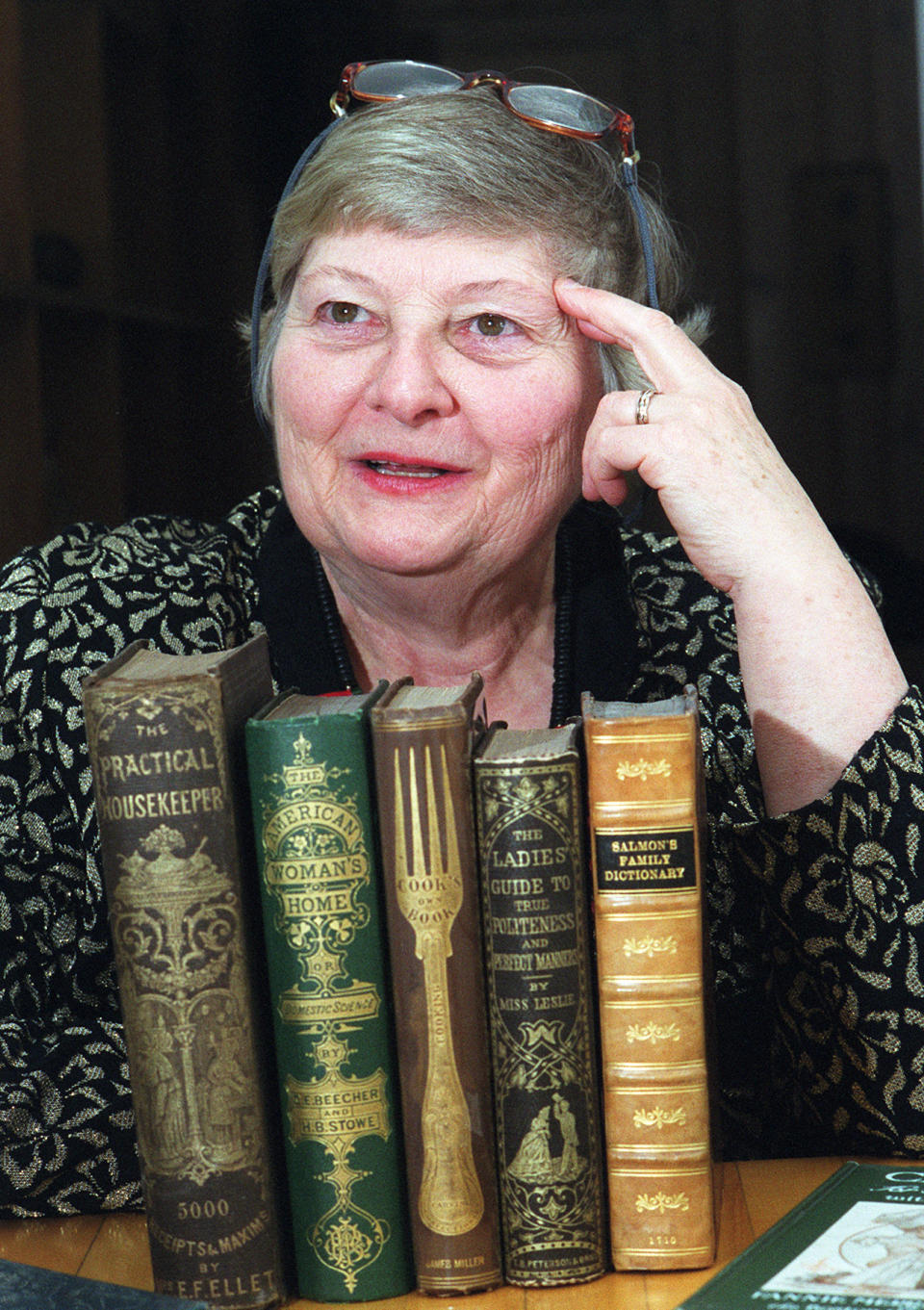 Janice Longone poses with some of her collection of cookbooks spanning 300 years. Longone, who is credited with collecting thousands of items chronicling the culinary history of the United States, including cookbooks, menus, advertisements and diaries, died Wednesday, Aug. 3, 2022, according to Nie Family Funeral Home in Ann Arbor. She was 89. (Robert Chase/Ann Arbor News via AP)