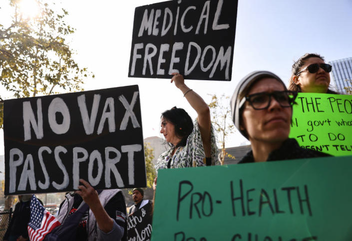 Protesters at a rally against a COVID vaccine mandate hold signs saying no vax passport and medical freedom.
