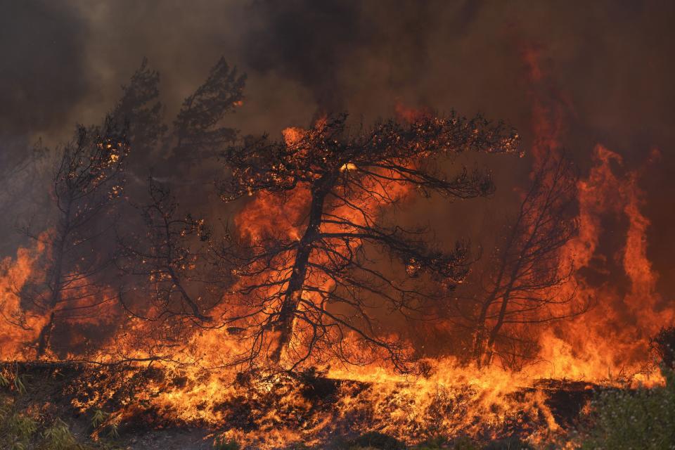 Flames burn a forest in Vati village, on the Aegean Sea island of Rhodes, southeastern Greece, on Tuesday, July 25, 2023. A third successive heat wave in Greece pushed temperatures back above 40 degrees Celsius (104 degrees Fahrenheit) across parts of the country Tuesday following more nighttime evacuations from fires that have raged out of control for days. (AP Photo/Petros Giannakouris)