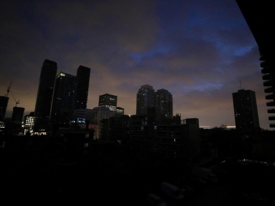 Blacked-out residential buildings are silhouetted against the sky during a short electrical power outage in midtown Toronto on Jan. 6, 2023. At the peak of the outages, the utility says about 40,000 customers had been affected, Toronto Hydro says. (Chris Helgren/Reuters - image credit)