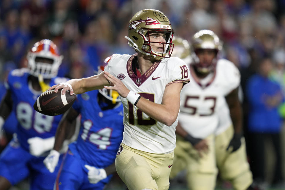 Florida State quarterback Tate Rodemaker (18) looks for a receiver as he is pressured by Florida safety Jordan Castell (14) and defensive lineman Caleb Banks (88) during the first half of an NCAA college football game Saturday, Nov. 25, 2023, in Gainesville, Fla. (AP Photo/John Raoux)