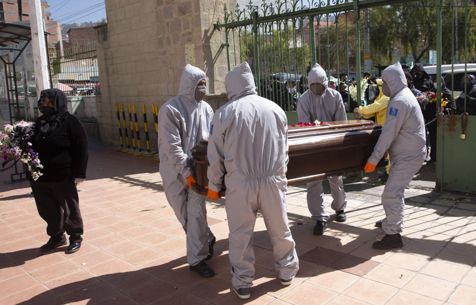 Funeral home workers wearing full protective gear as a precaution against the spread of the new coronavirus, carry the coffin of a man, whose death was not related to COVID-19, into the General Cemetery in La Paz, Bolivia, Tuesday, July 21, 2020. (AP Photo/Juan Karita)