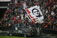 The remains of the Portuguese soccer player legend Eusebio are carried inside a car as supporters cheer during his memorial tribute at the Benfica's Luz stadium in Lisbon, Monday, Jan. 6, 2014. Eusebio, the Portuguese football star who was born into poverty in Africa but became an international sporting icon and was voted one of the 10 best players of all time, has died aged 71, his longtime club Benfica said. Few supporters hold posters with the photograph of Eusebio that read in Portuguese: "Bye King". (AP Photo/Francisco Seco)