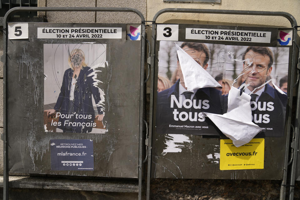 Defaced posters are seen outside a polling station in Paris, France, Sunday, April 24, 2022. France began voting in a presidential runoff election Sunday with repercussions for Europe's future, with centrist incumbent Emmanuel Macron the front-runner but fighting a tough challenge from far-right contender Marine Le Pen. (AP Photo/Francois Mori)