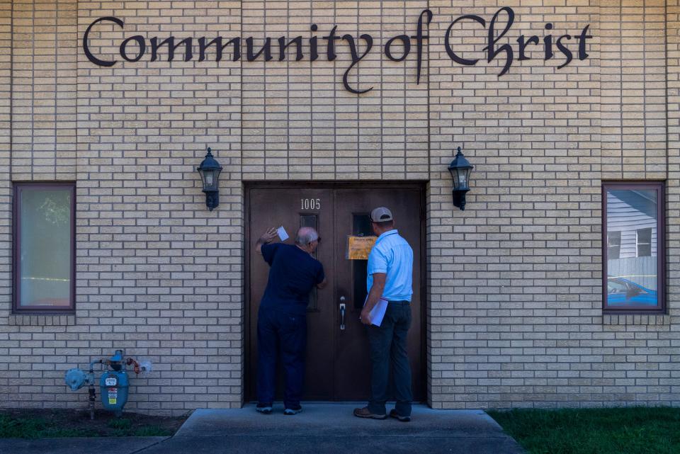 Elder Richard Gregg, left, gets information from Evansville-Vanderburgh Building Commission’s Eric Wade, right, after his church Community of Christ on Hercules Avenue was tagged “unsafe” the morning after a house explosion in the 1000 block of North Weinbach Avenue in Evansville, Ind., Thursday, Aug. 11, 2022. 