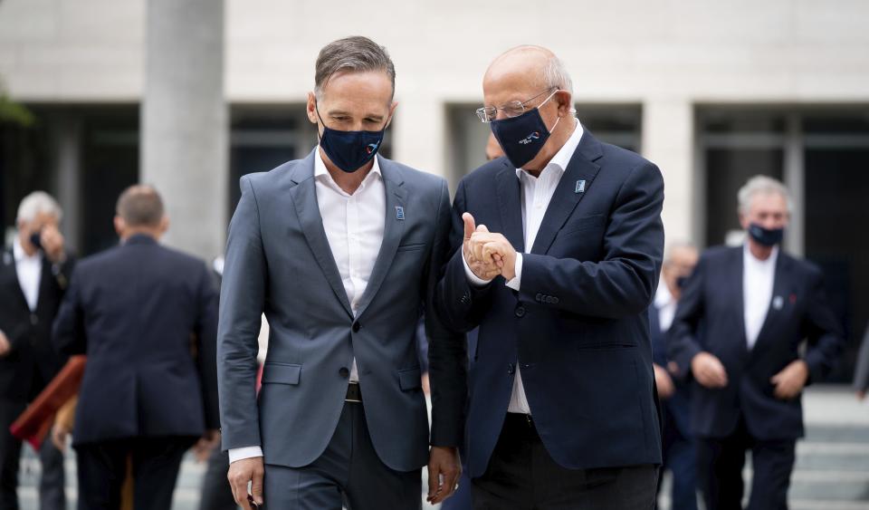 Foreign Minister Heiko Maas wearing a mouth-and-nose protector, left, talks to his Portuguese counterpart Augusto Santos Silva at a family photo on the sidelines of the informal talks between the EU Foreign Ministers in Berlin, Germany, Friday, Aug. 28, 2020. The topics of the so-called Gymnich meeting include developments in Belarus and the dispute over natural gas in the eastern Mediterranean between Turkey and the EU states of Greece and Cyprus. (Kay Nietfeld/dpa via AP)